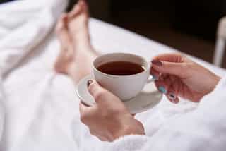A cup of herbal tea with dried flowers and herbs.